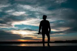 silhouette of man standing holding camera